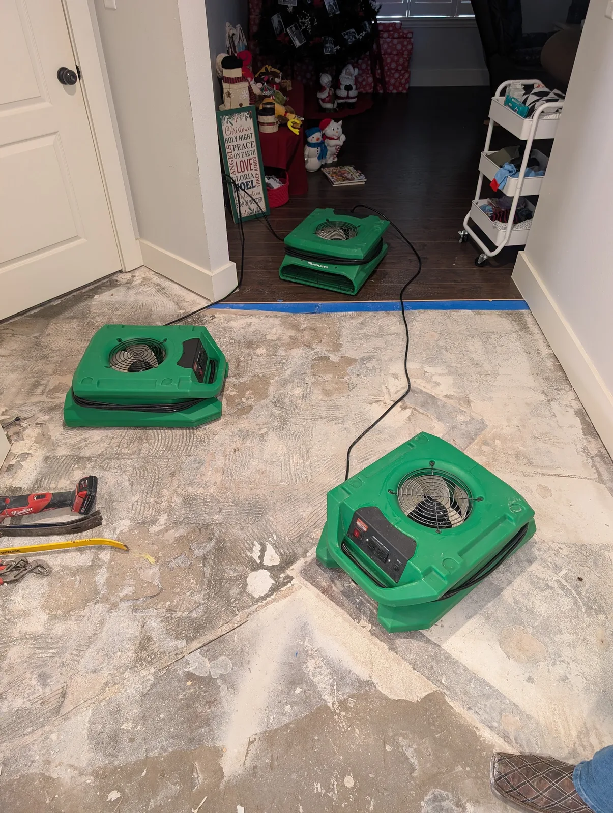 Air movers drying a water-damaged floor down to the slab in an occupied North Texas home