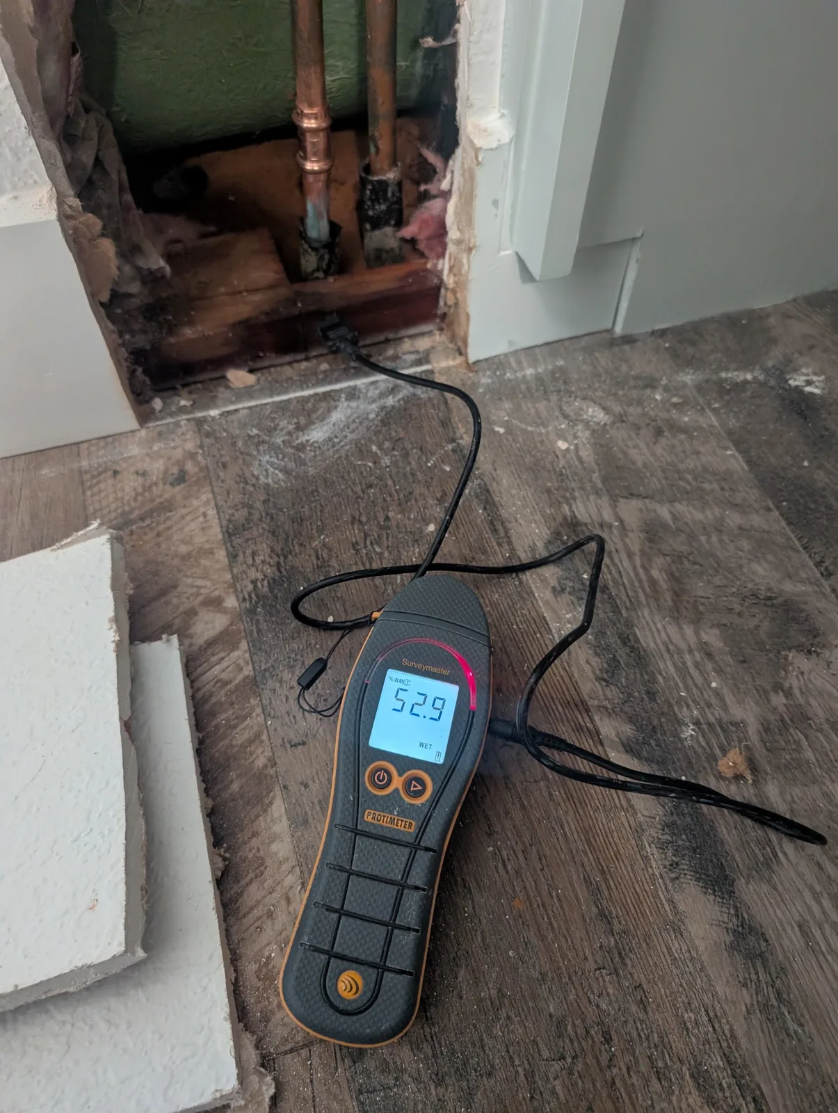 Protimeter moisture meter reading 52.9 percent WME at an opened wall during water damage inspection